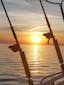 Two fishing rods at sunset perched aside a boat